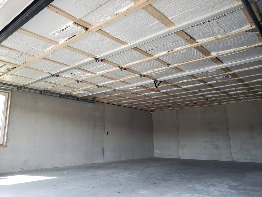 Panneaux isolants vissés au plafond d'un garage, sous le plancher de l'étage